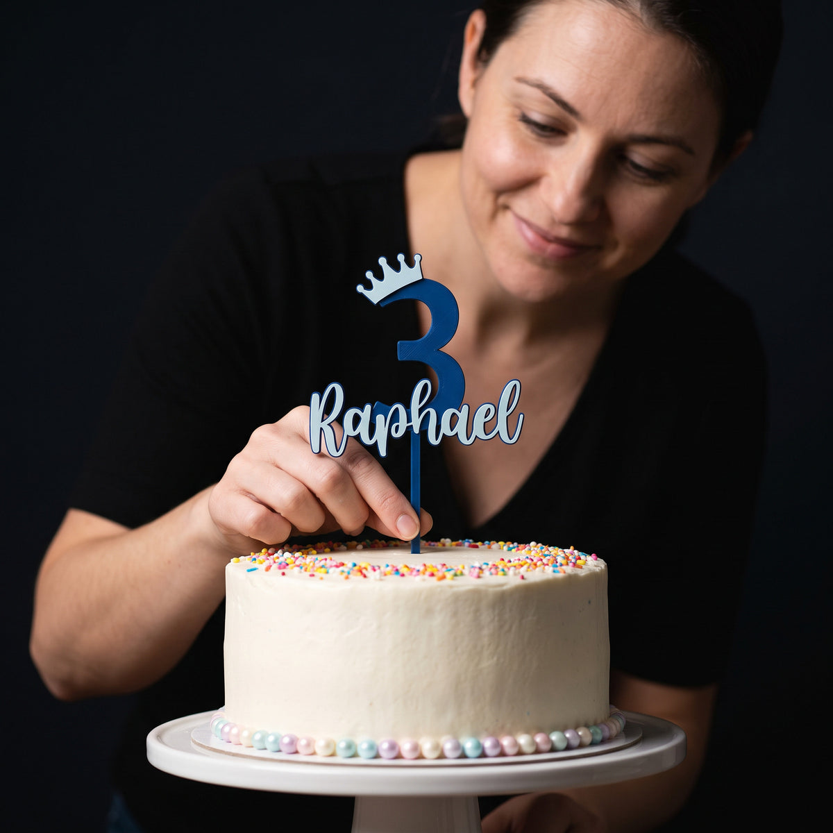 Cake Topper Zahl mit Krone und Name in Blau und Eisblau wird in eine Geburtstagstorte gesteckt