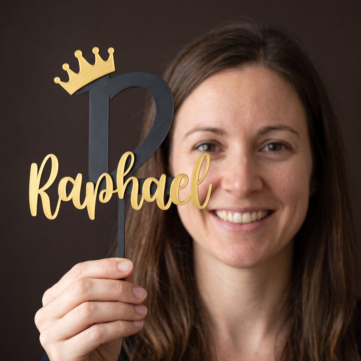 Frau hält den Cake Topper Zahl mit Krone zum 12. Geburtstag in Schwarz und Gold in der Hand