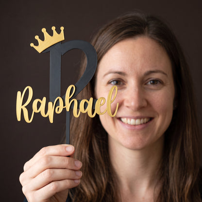Frau hält den Cake Topper Zahl mit Krone zum 12. Geburtstag in Schwarz und Gold in der Hand