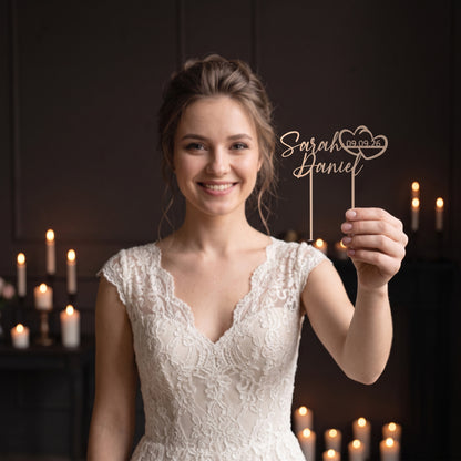 Braut hält Cake Topper Namen mit Doppelherz in Champagner
