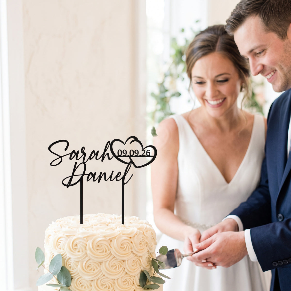 Brautpaar schneidet Torte mit Cake Topper Namen mit Doppelherz